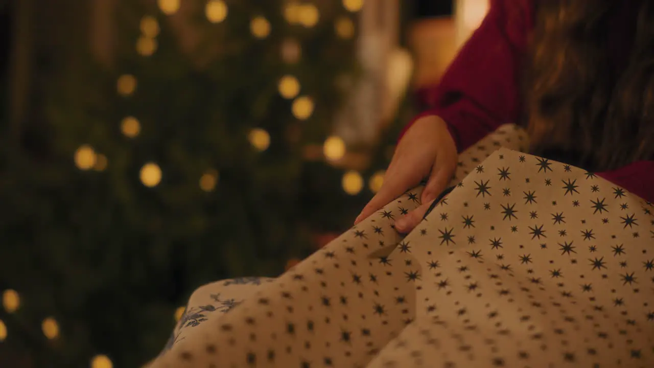 Woman cutting paper while wrapping Christmas gift