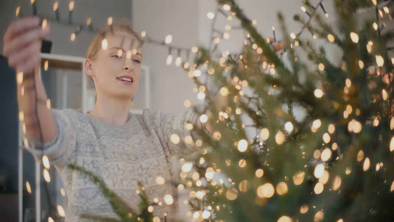 Woman decorating Christmas tree at home