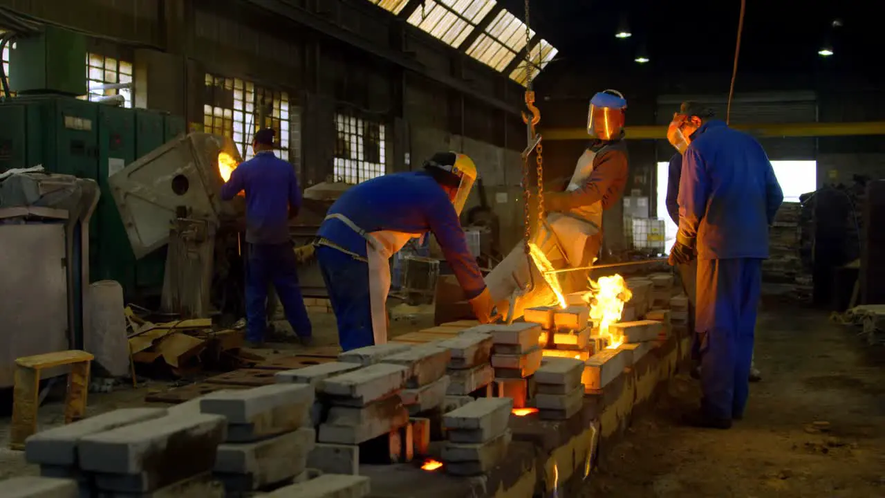 Worker pouring molten metal from container in foundry workshop 4k