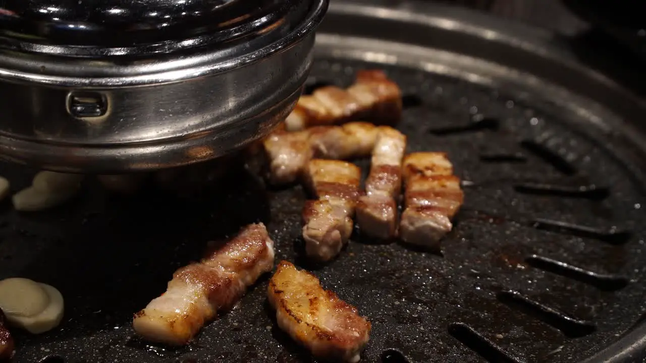 Pork belly getting seared on traditional Korean barbecue in restaurant