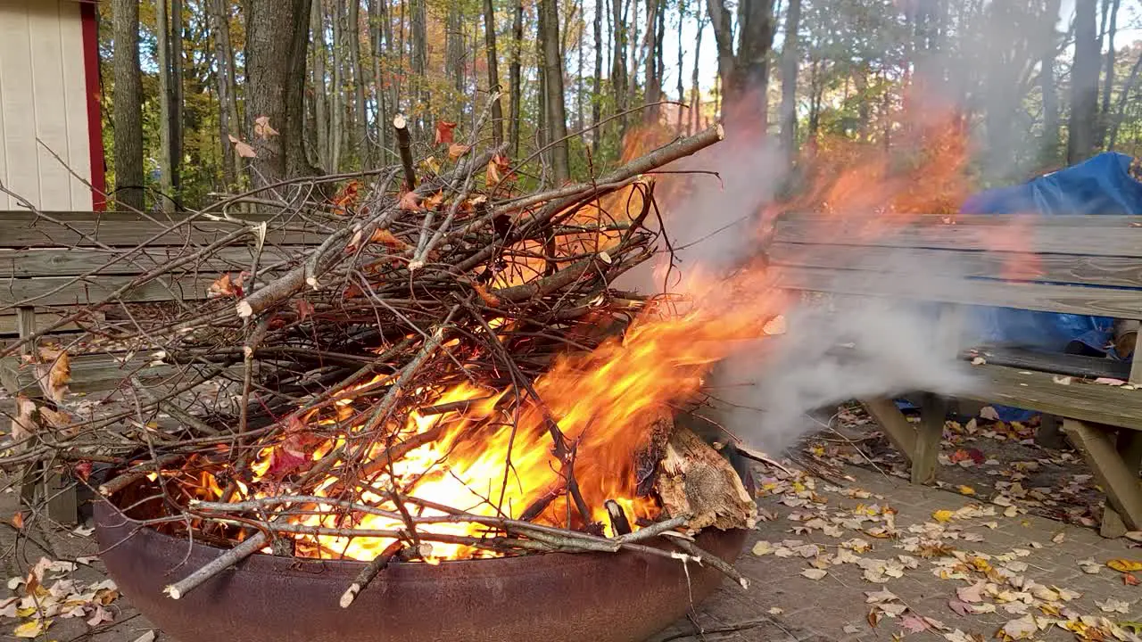 Pot Of Tree Branches On Fire In Big Pot In Windy Day While Man Passing In Front