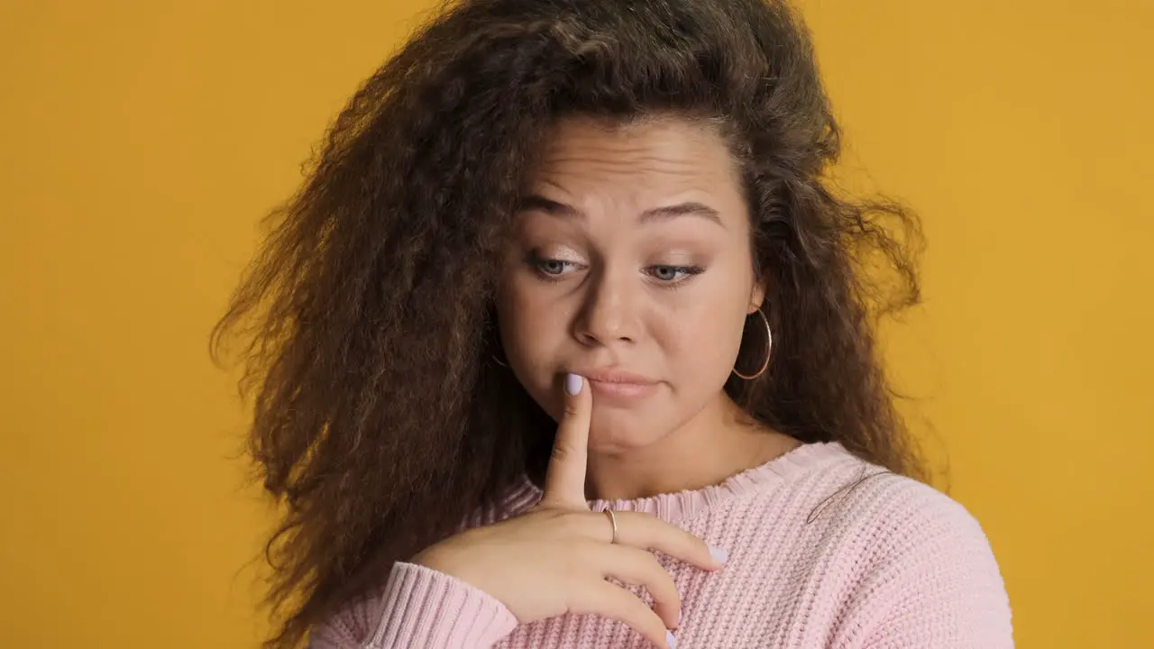 Thoughtful Caucasian curly haired woman in front of the camera