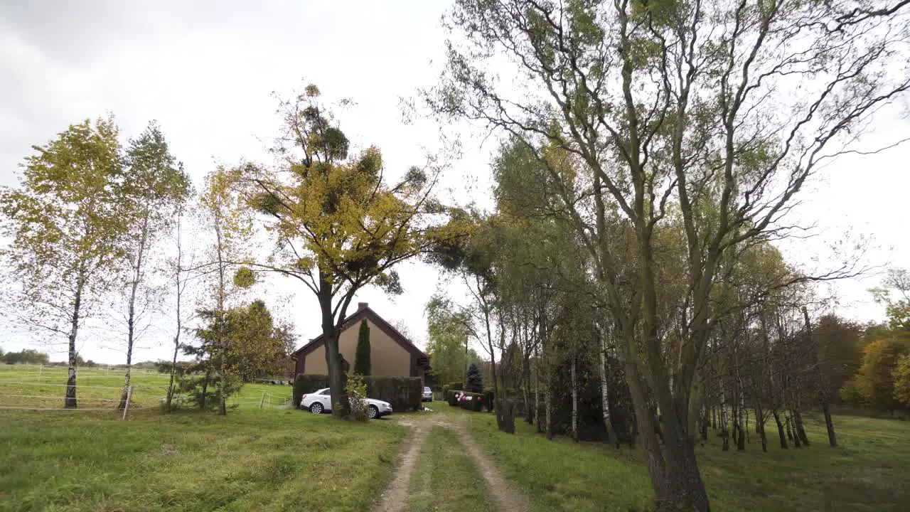 Home road with backyard garden lonely house and autumn colorful trees in cloudy day