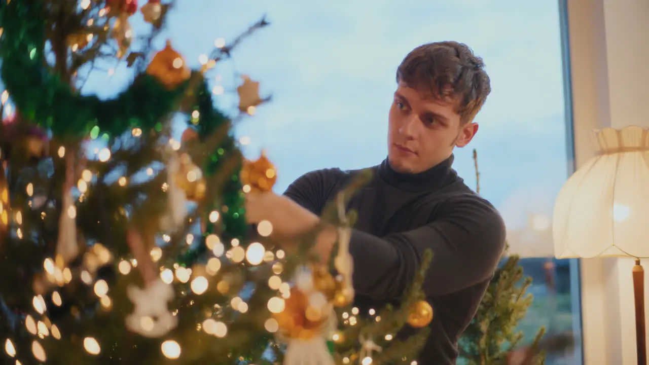 Man decorating Xmas tree with bauble at home