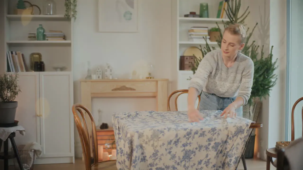 Woman putting tablecloth while setting table