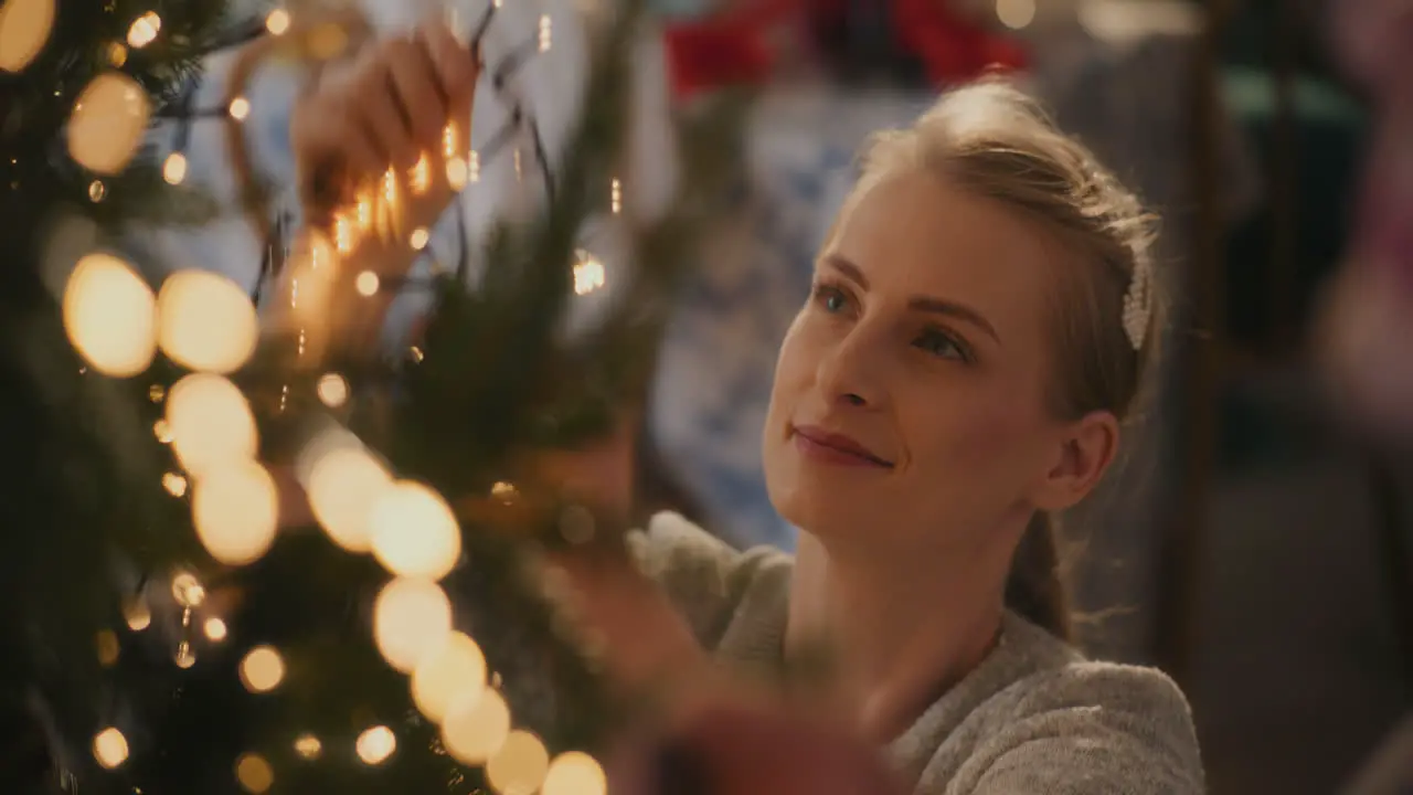 Young woman adjusting glowing led lights on tree