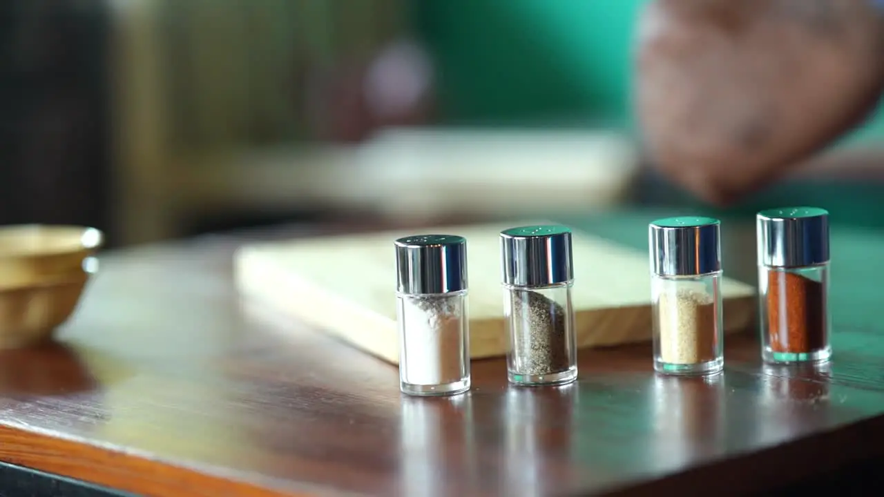 Condiments Shakers Being Placed On Table For Presentation Slow Motion With Bokeh Background