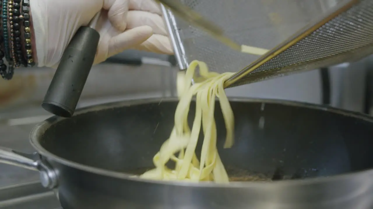 A professional chef in Italy is prepairing a plate of pasta and scampi in his kitchen 04