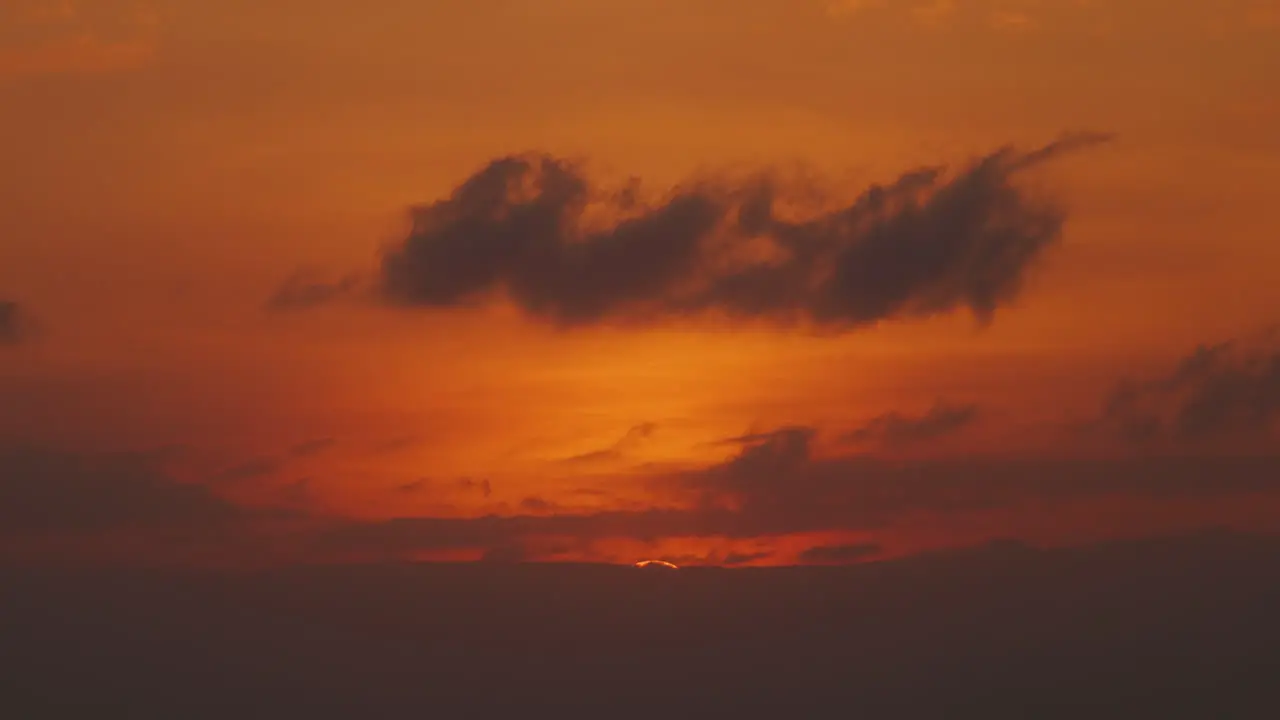 Orange warm sunset time lapse with big sun hiding behind clouds