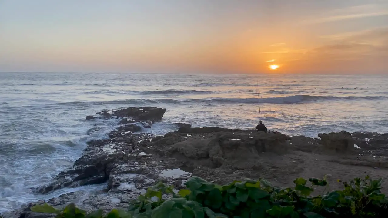 An experienced fisherman trying to fish with a professional spinning rod on the rocks with the lapping sea