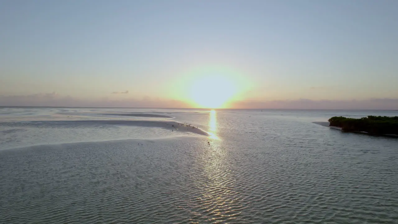 Drone view of waves on the beach with blue sky and sunset