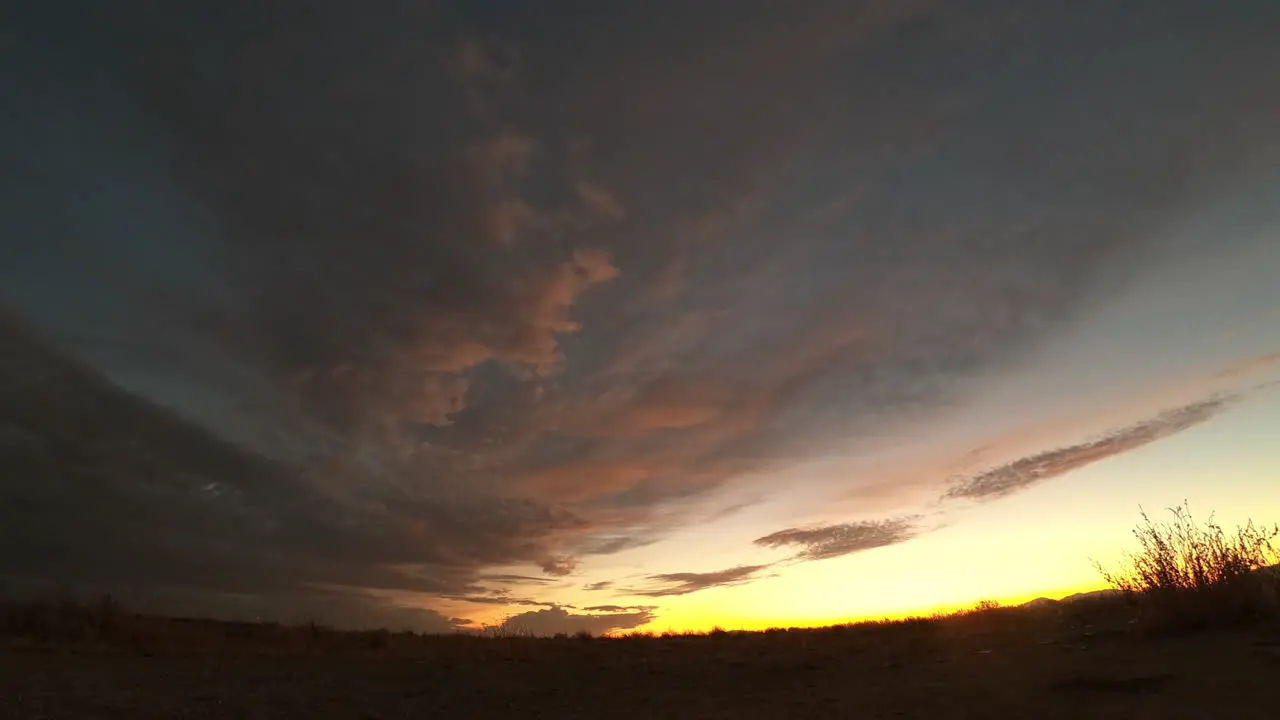 Pink and golden sunset slowly fades to darkness in Mojave Desert plain