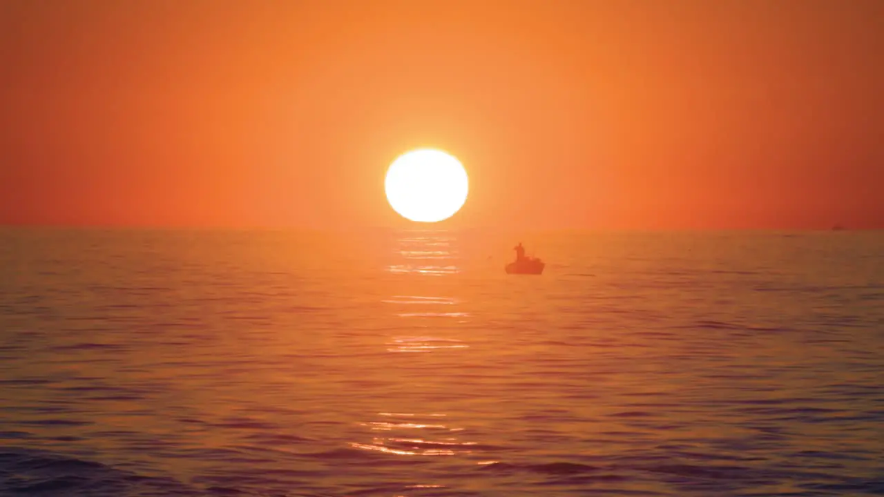 Vibrant sunrise over the ocean with fishing boats in the distance