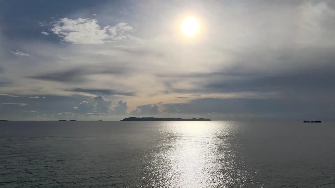 Aerial view of low setting sun in cloudy sky reflecting on calm sea