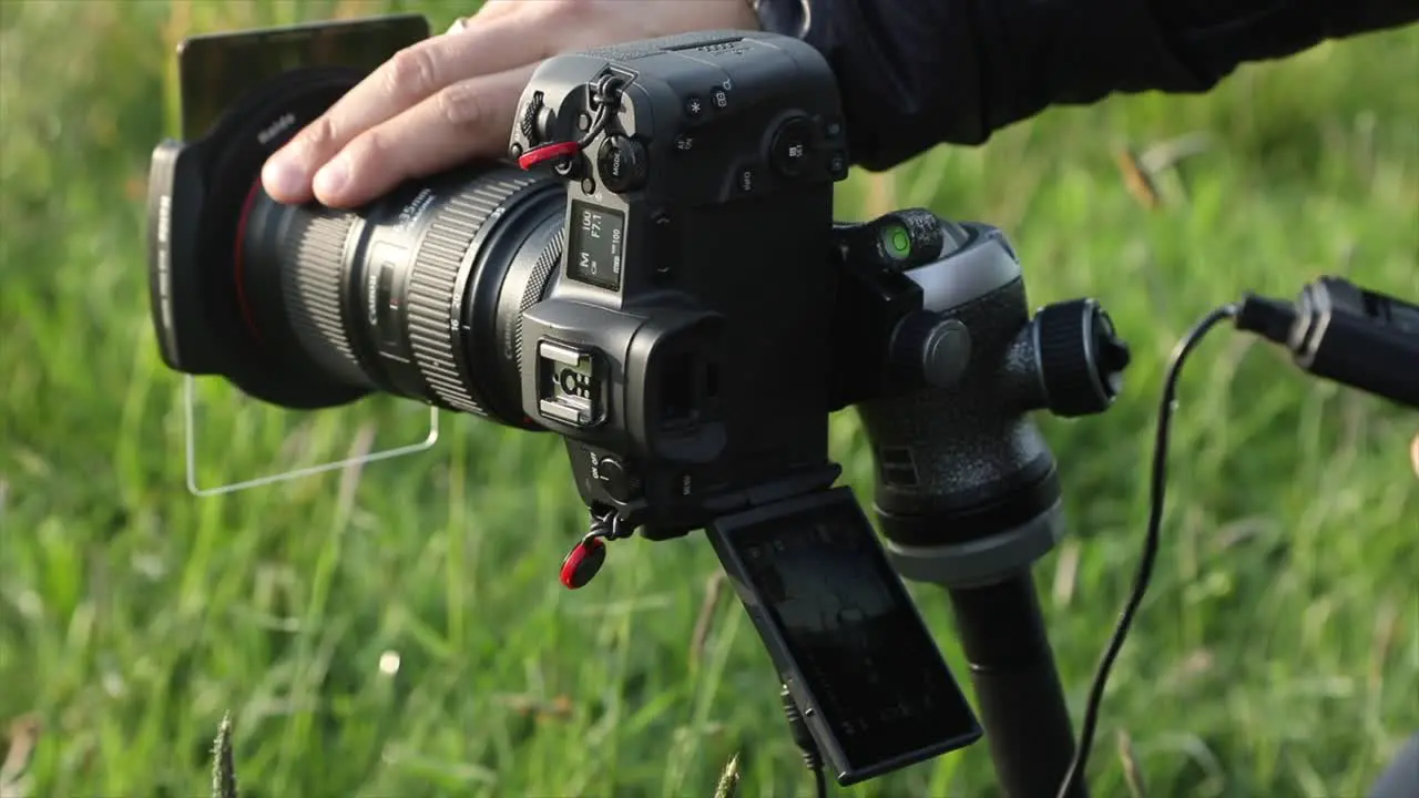 Photographer sets the shot on a camera mounted on a tripod and selects the focus takes the picture with an intervalometer