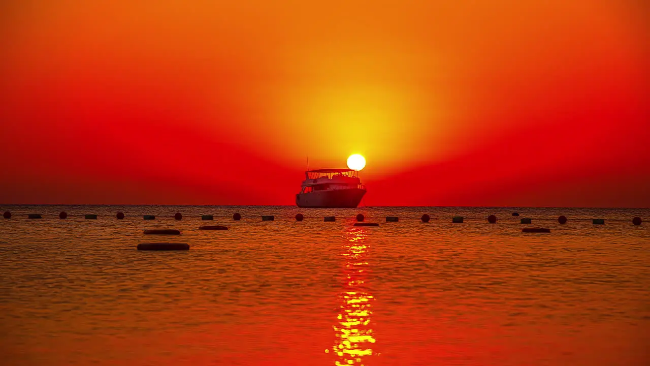 Silhouette of ship on sea during red colored sunset at horizon time lapse