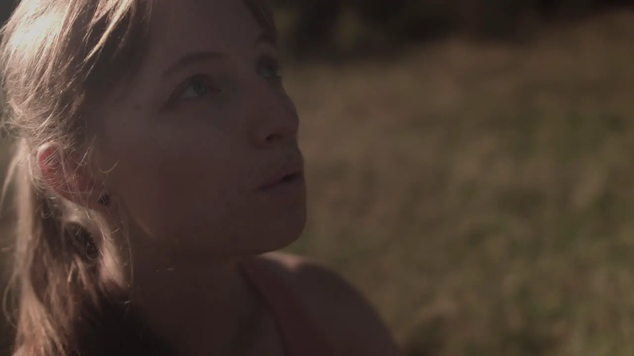 A girl is shown in close-up while taking a deep breath gazing at the sky and then closing her eyes for meditation