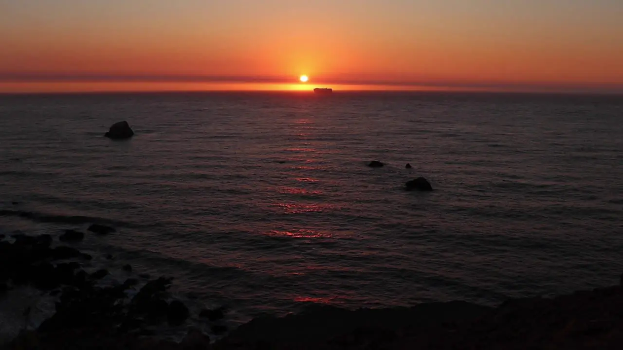 Beautiful golden sunset along the Northern California Coast with a ship crossing the sun meeting the horizon on a calm summer night