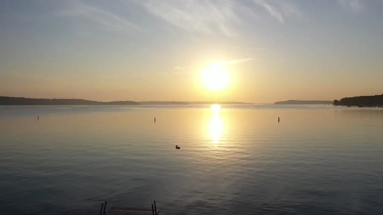 aerial shot headed towards the golden hour sunset taking off from the sandy beach over the lake