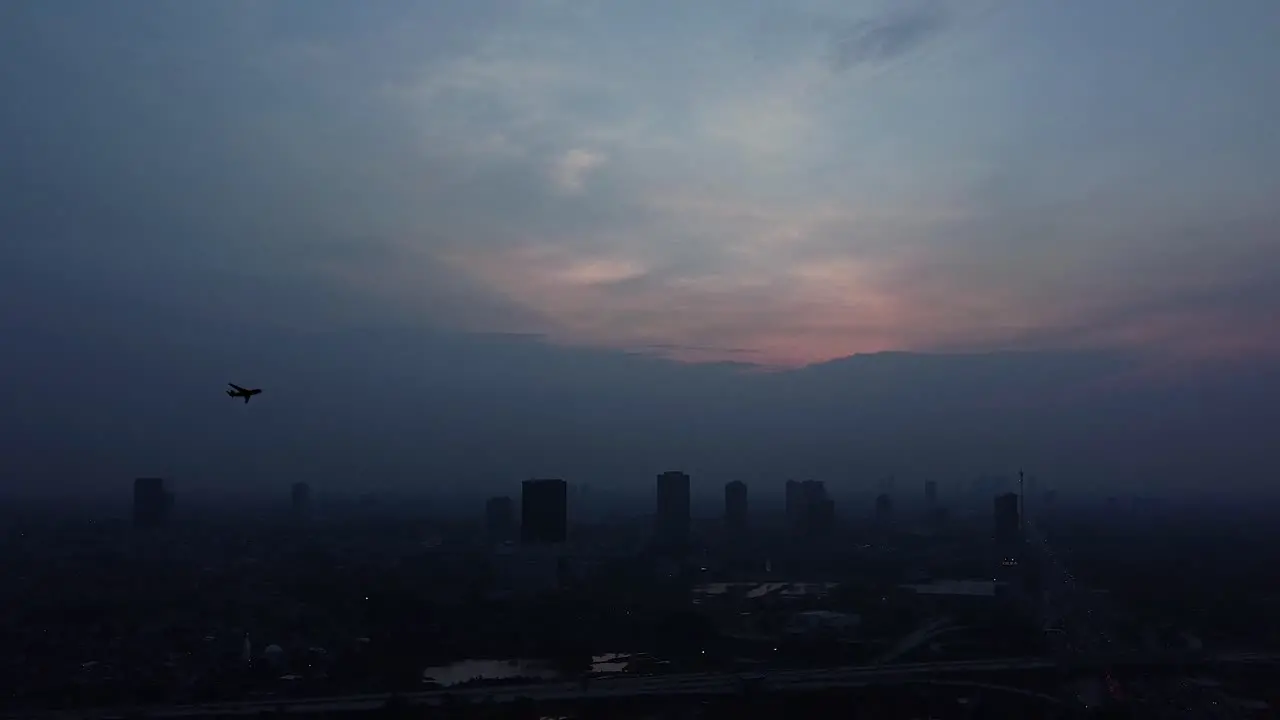 airplane passing over a city at dusk