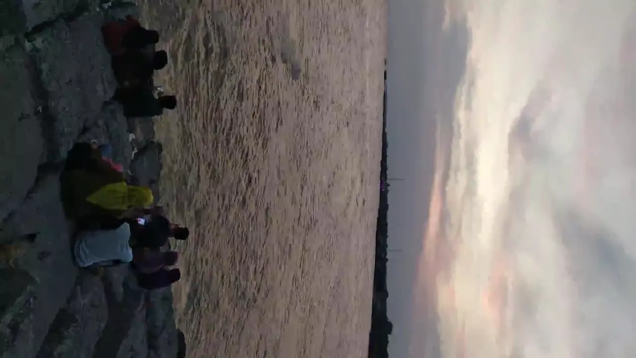 People enjoy the dramatic twilight sky over the beach