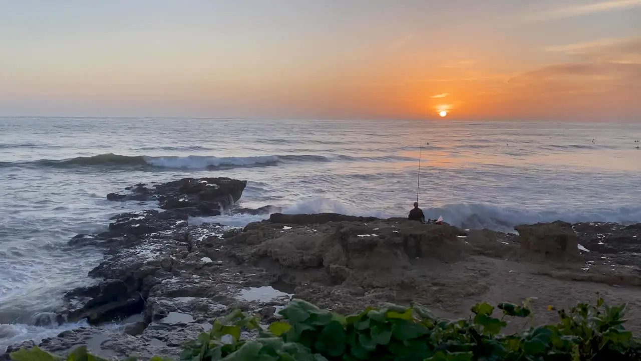 Silhouette of fisherman fishing at sunset with spinning rod