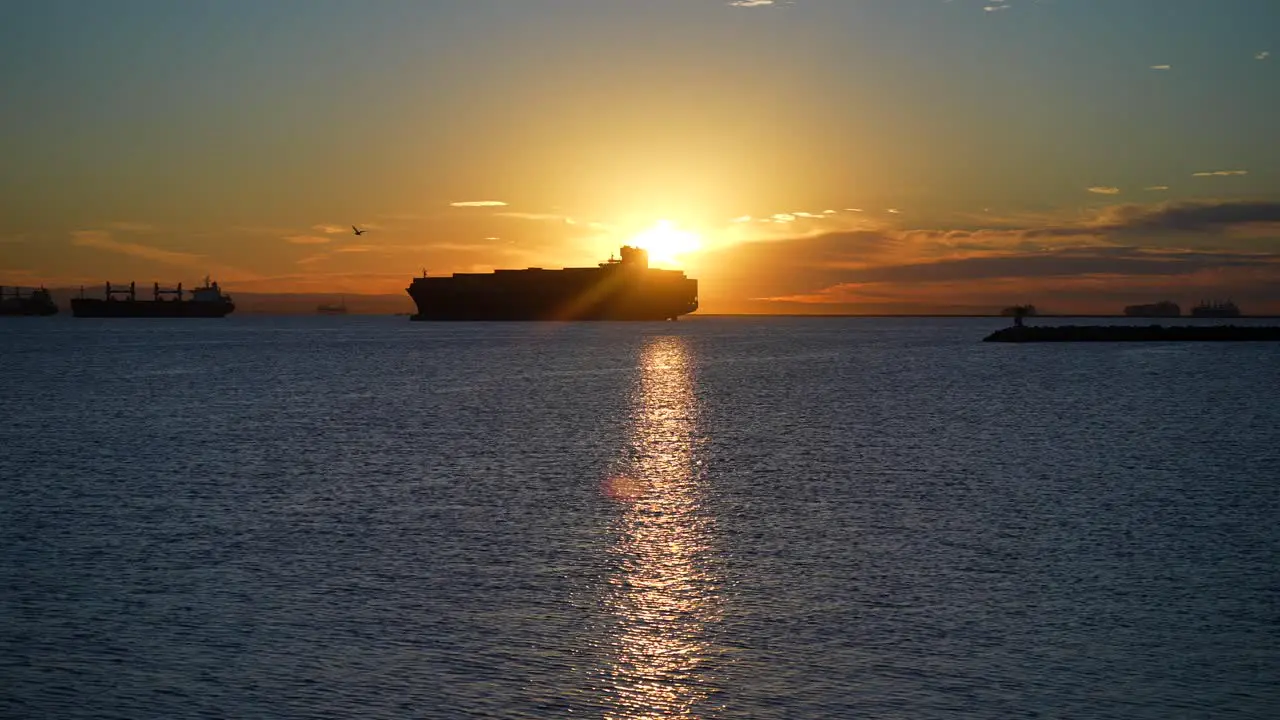 Silhouette of a cargo container ship in the harbor amidst a global supply chain crisis at sunset