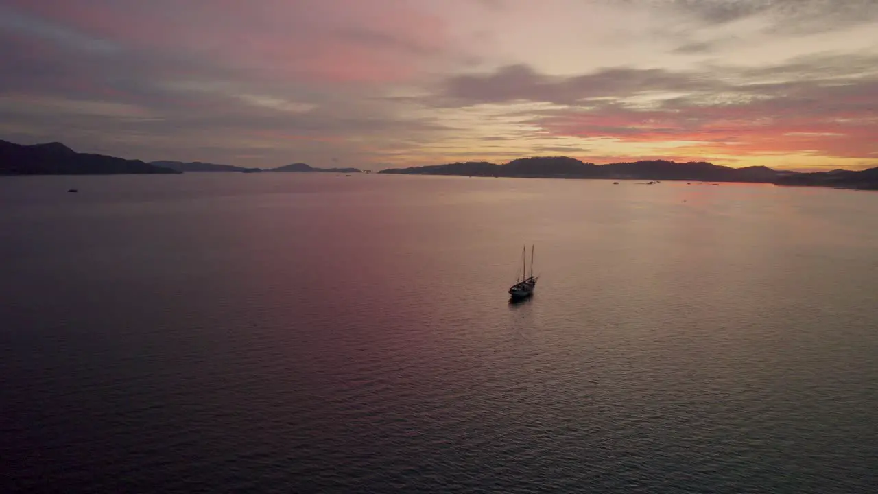 Aerial shot of a small boat anchored at sea with a stunning sunset