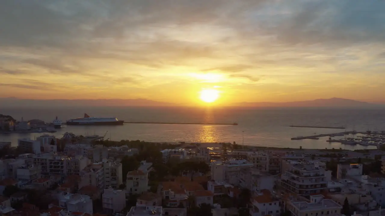 Aerial drone Flight over downtown mitilini revealing golden sunrise at sea with ferry to athens lesvos greece