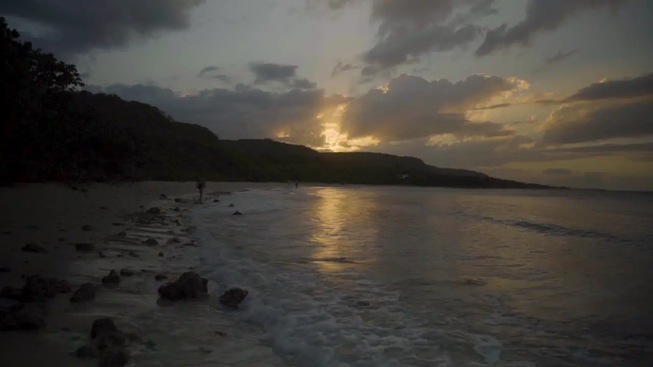 Gliding down a beach towards a beautiful sunset as waves crash onto the beach in slow motion