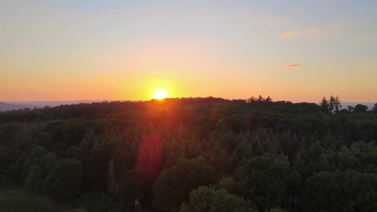 Low drone flight over deciduous trees during an extremely colourful sunset in Germany's countryside