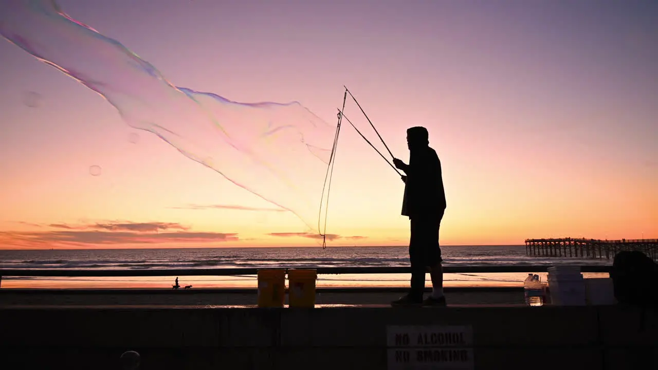 The wind blowing beautiful soap bubbles in the air with the colors of sunset in the background wide shot