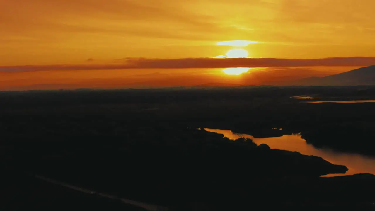 Aerial drone footage of the sun rising above the pine tree forest in the iconic Maremma nature park in Tuscany Italy with a dramatic cloud sky above the savannah lagoon