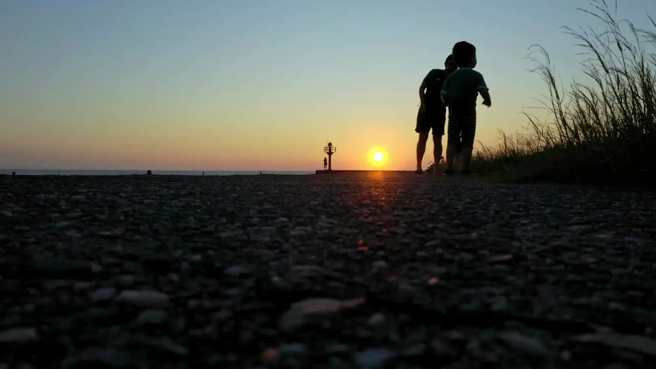 Low angle shot showing silhouette of kids playing at beach during sunset in Taiwan