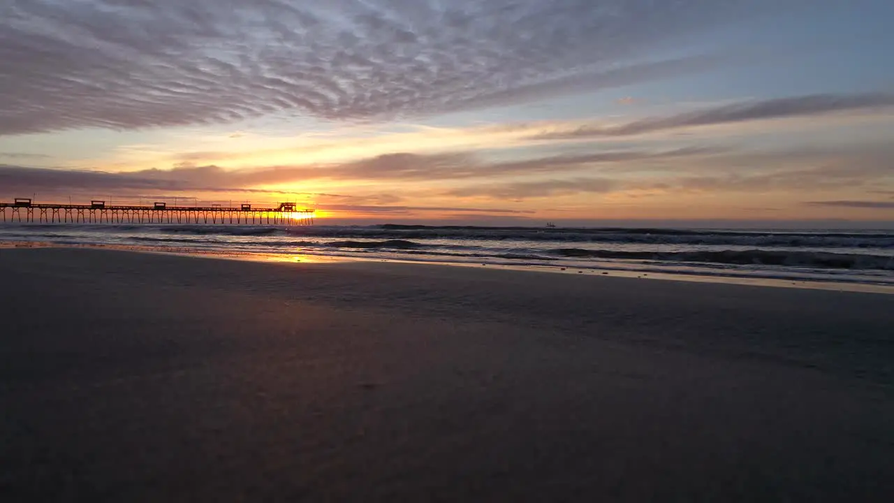 Waves hitting the coast of Emerald island the Bogue Inlet Pier at a sunny colorful dawn and sunrise in North Carolina