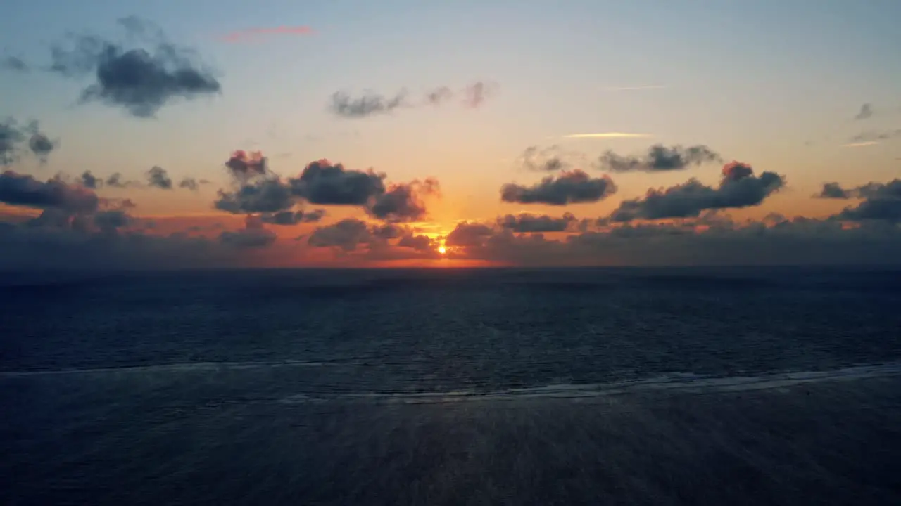 Beautiful aerial drone shot of a serene ocean sunrise at Well Beach near Joao Pessoa on a warm summer morning with the water below and golden clouds on the skyline