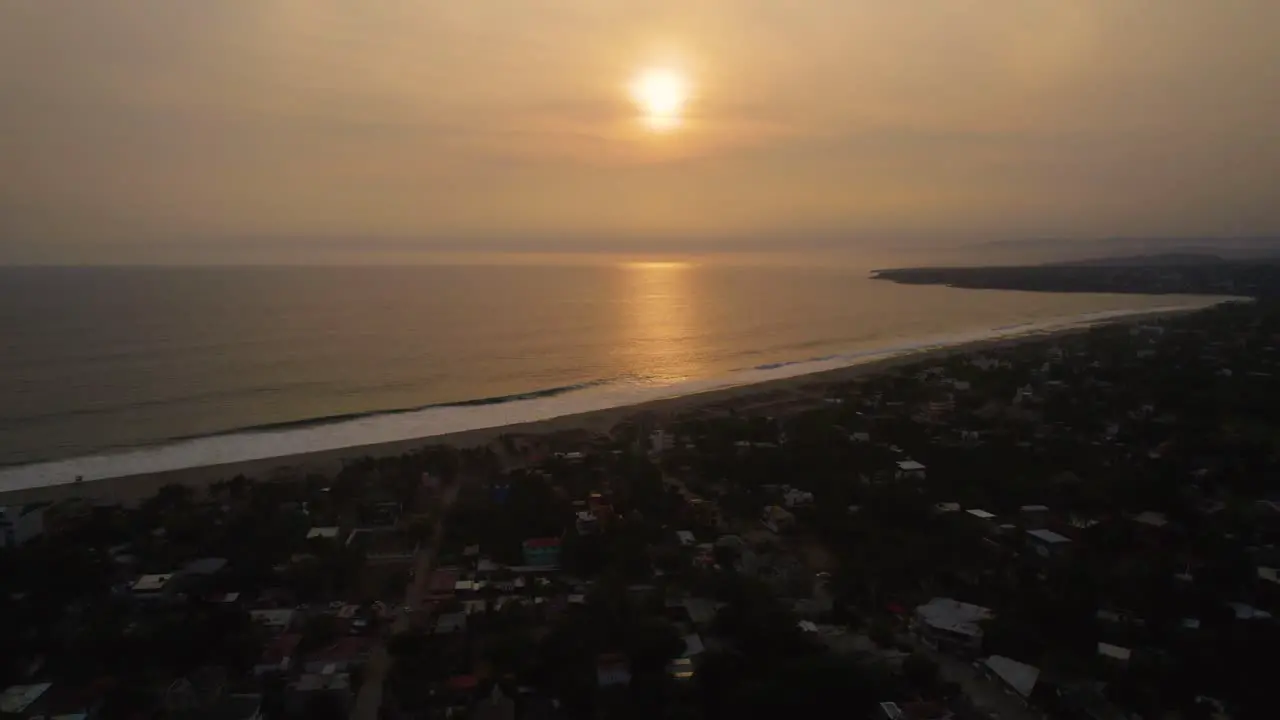 Backward aerial dolly shot with the sun setting over the ocean at Puerto Escondido