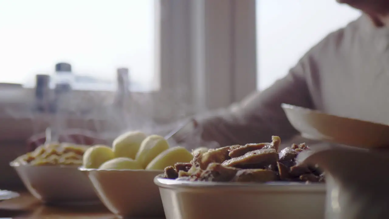 People sitting down to eat at table with steaming bowls of food