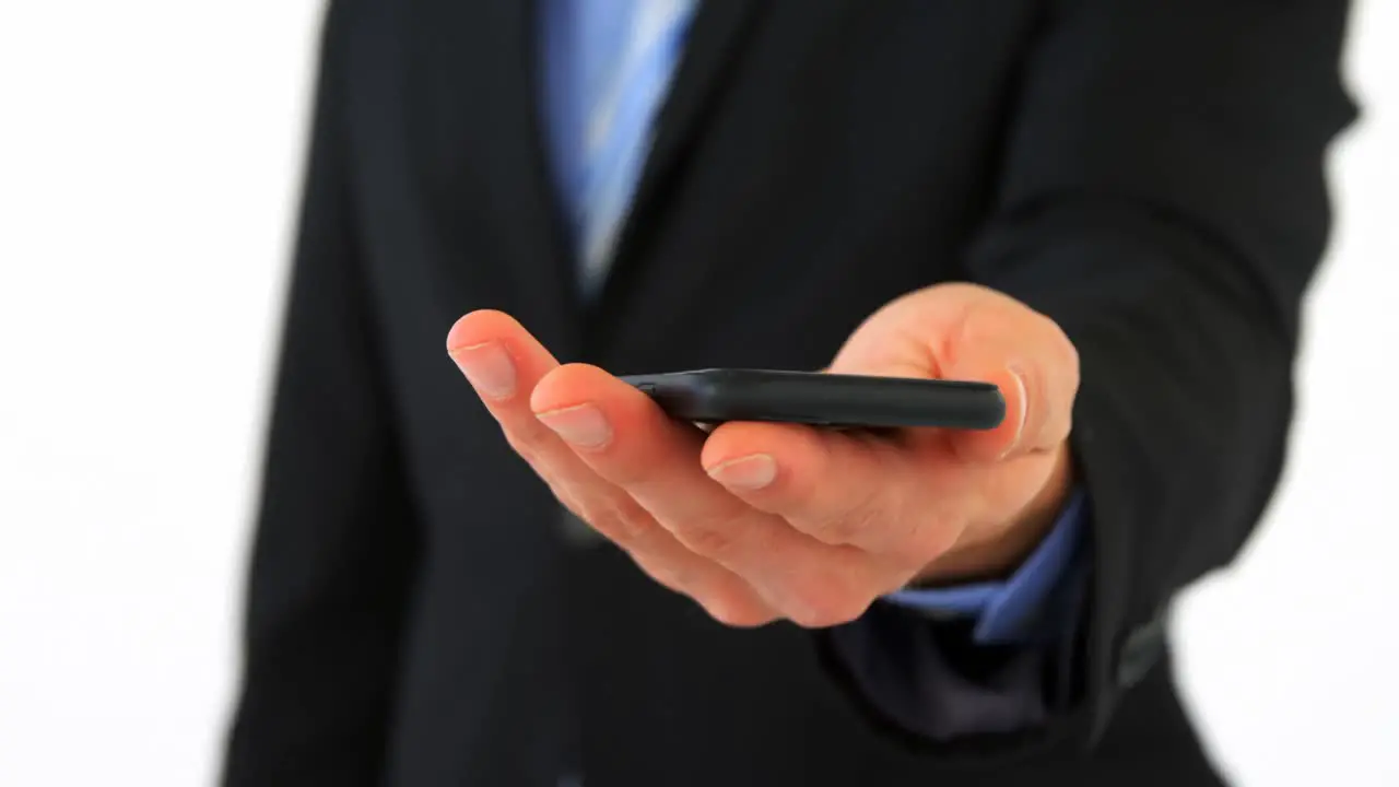 Mid section of businessman text messaging on mobile phone