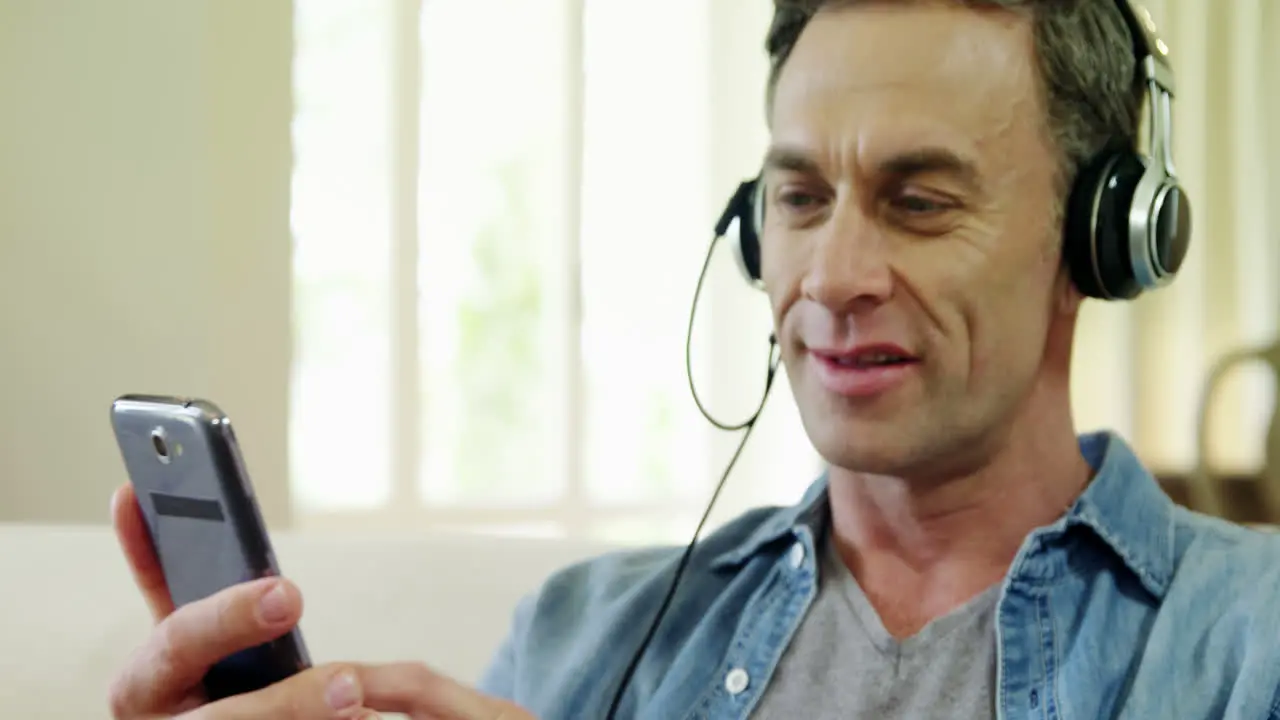 Man listening music on mobile in living room