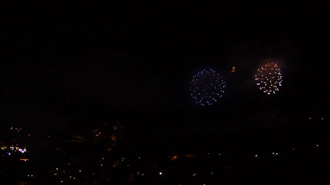 Celebration with many golden and sparkling fireworks over a mountain town at night