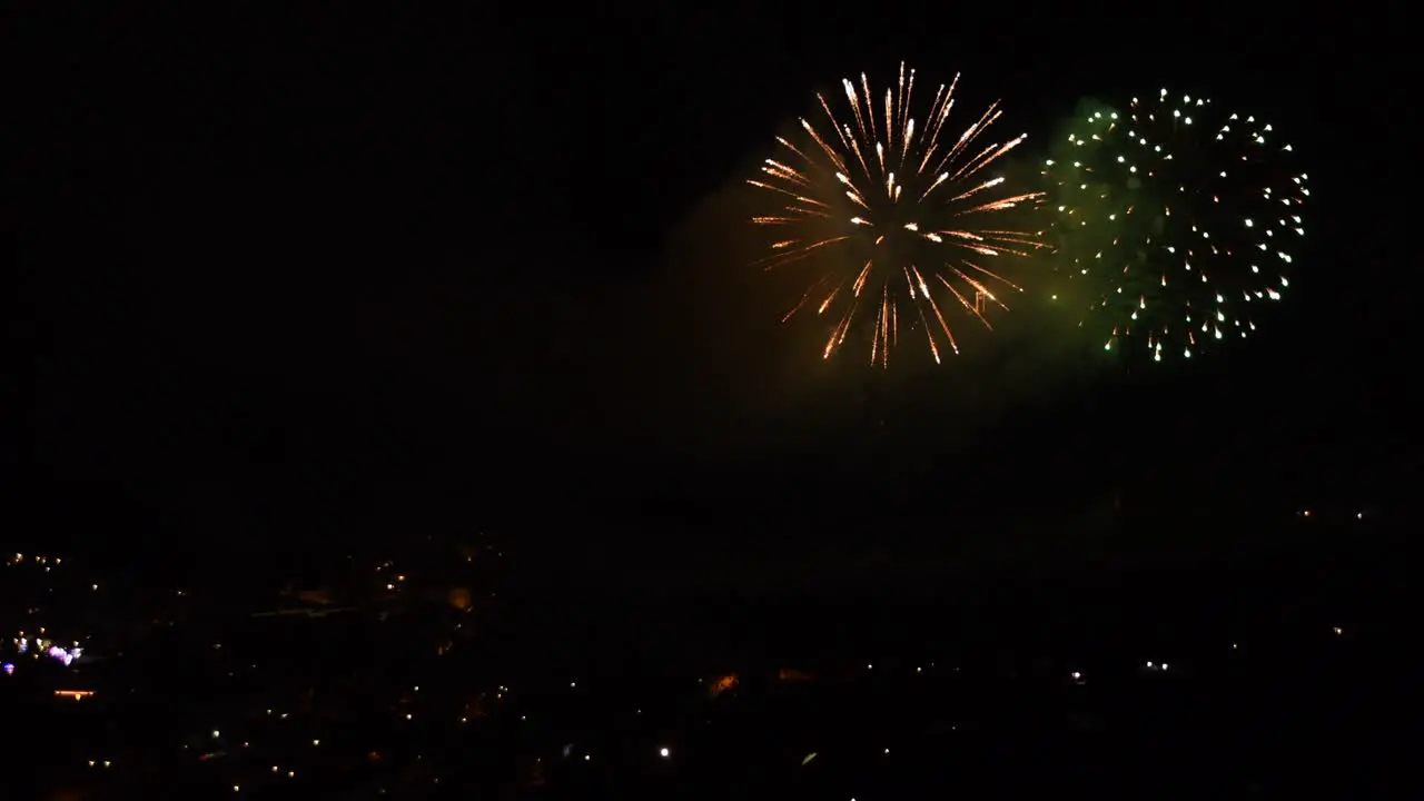 Celebration with many colorful fireworks over a mountain town at night