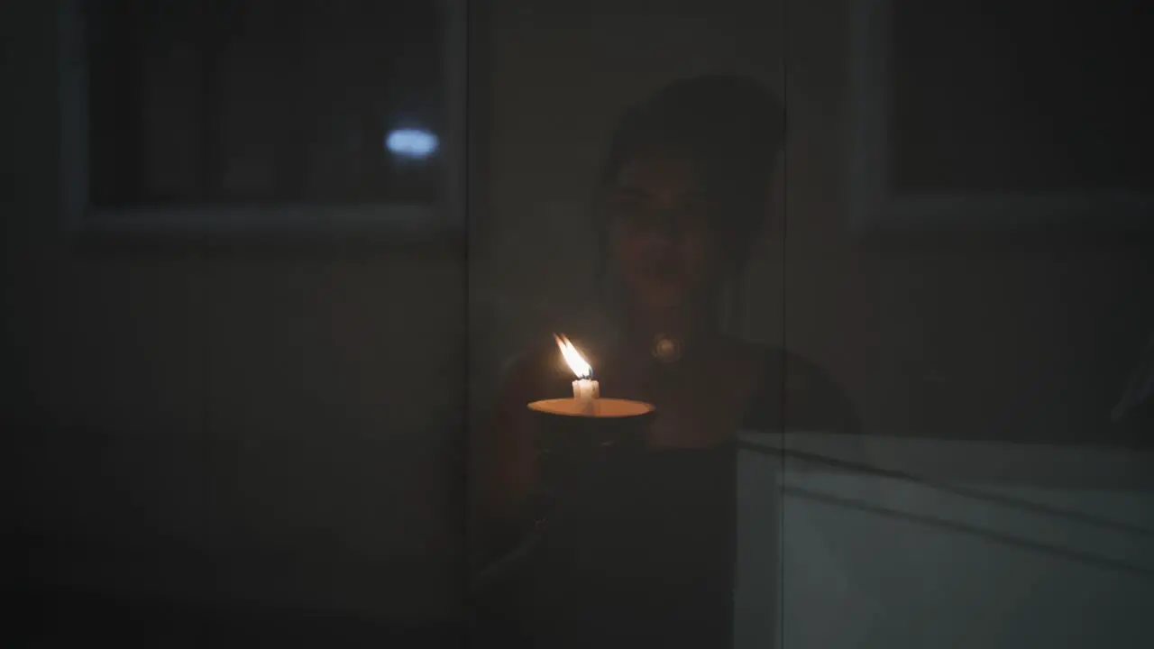 Close-up of a woman's hands lighting a candle with a match on the dark background