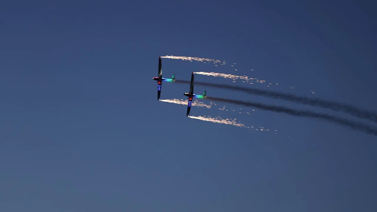 Tandem pyrotechnical aircraft releasing fireworks whilst flying in unison at night