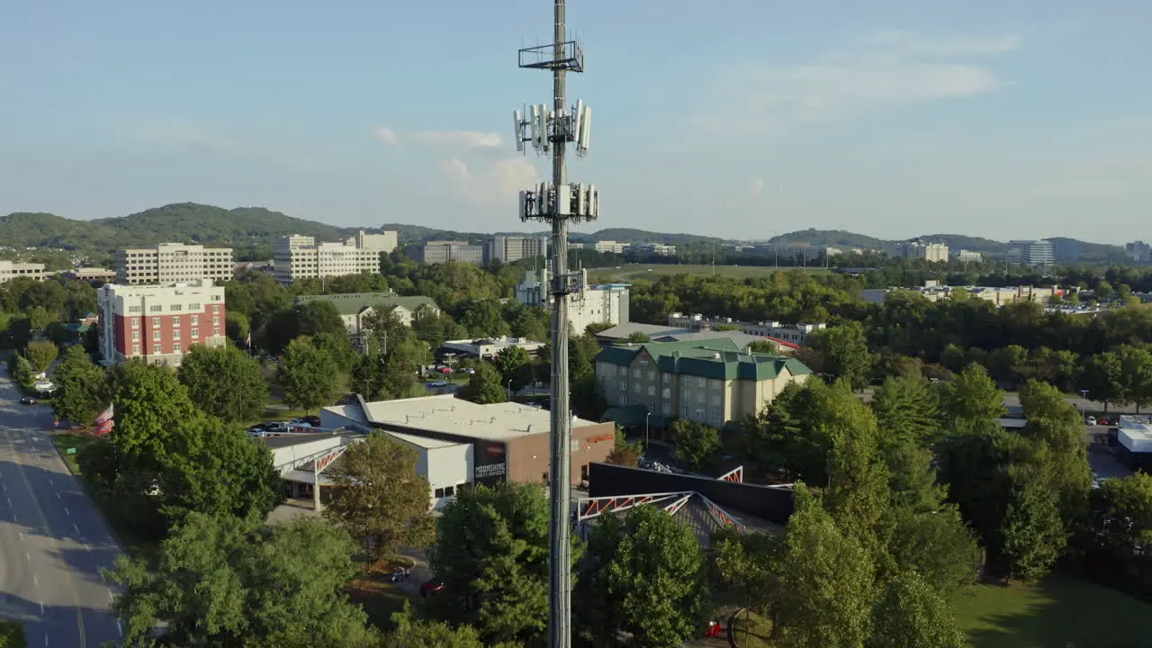 Aerial rising to reveal cell phone 5G communication tower in busy area 4K