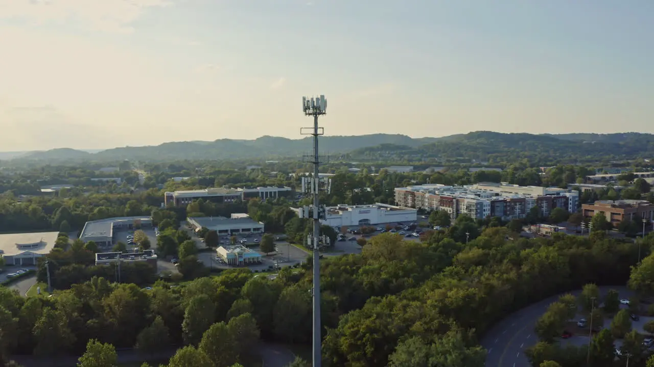 4K aerial rotating around 5G cell phone communication tower in afternoon