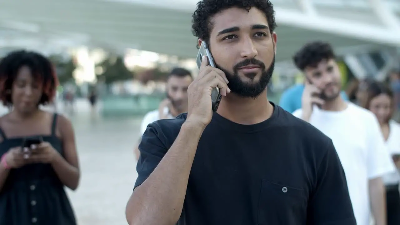 Front view of smiling young man talking on smartphone