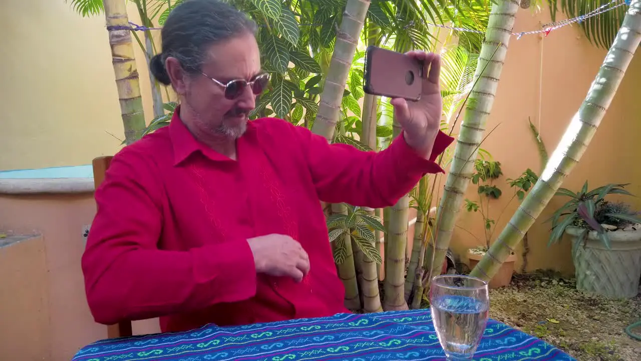 Mature man responding to someone on smartphone shows off his guayabera shirt