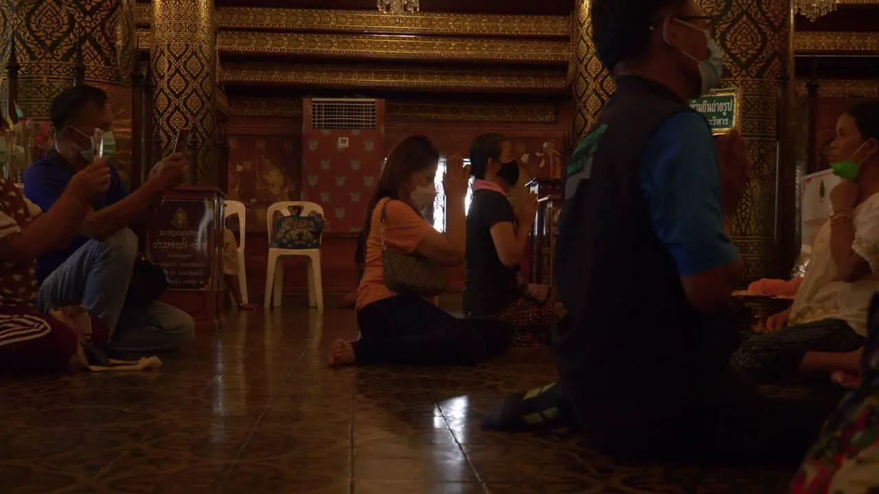 Men and women praying to Buddha inside Buddhist temple Wat Phra Sri Rattana Mahathat Thailand