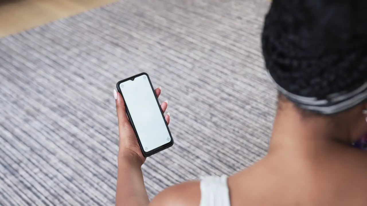 Young African American woman holds a smartphone at home with copy space